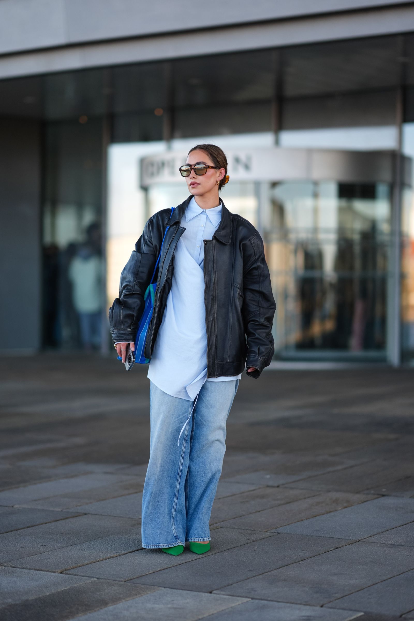 Mujer luce una blusa larga con jeans acampanados y chamarra de cuero en el street style