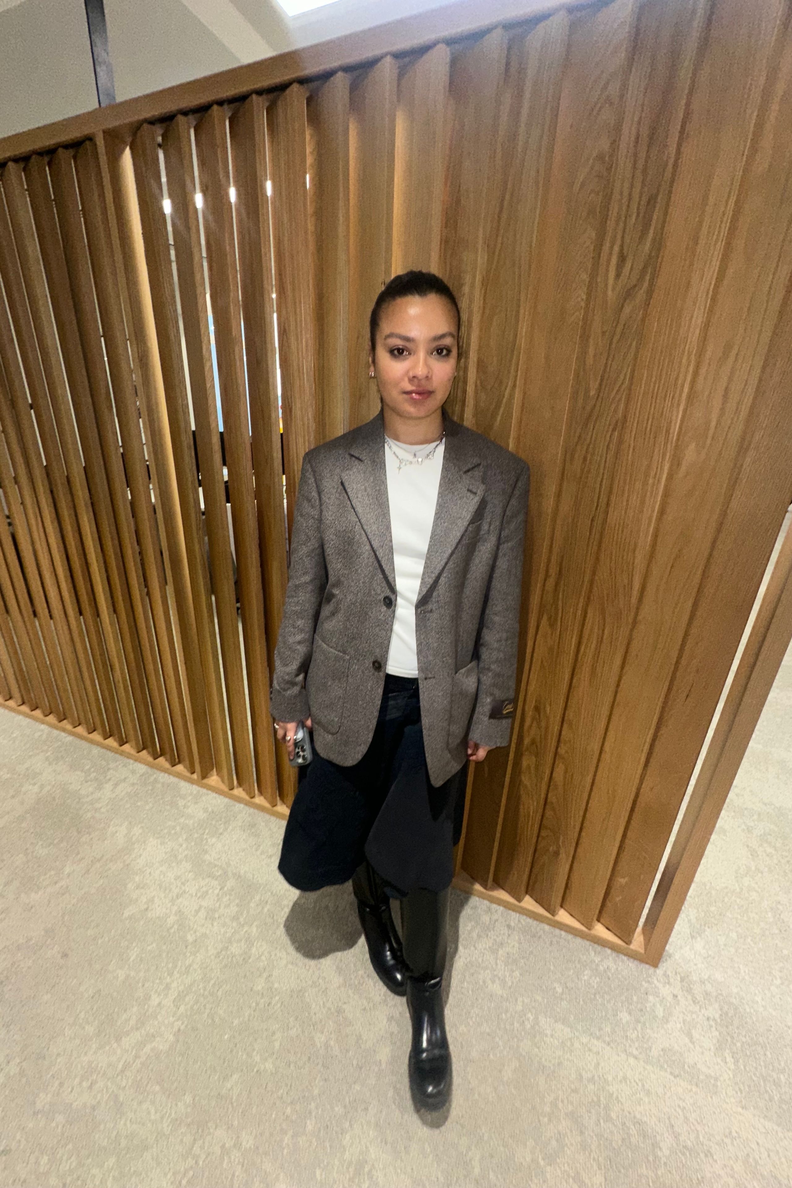 Image may contain Indoors Interior Design Person Standing Adult Clothing Coat and Sitting