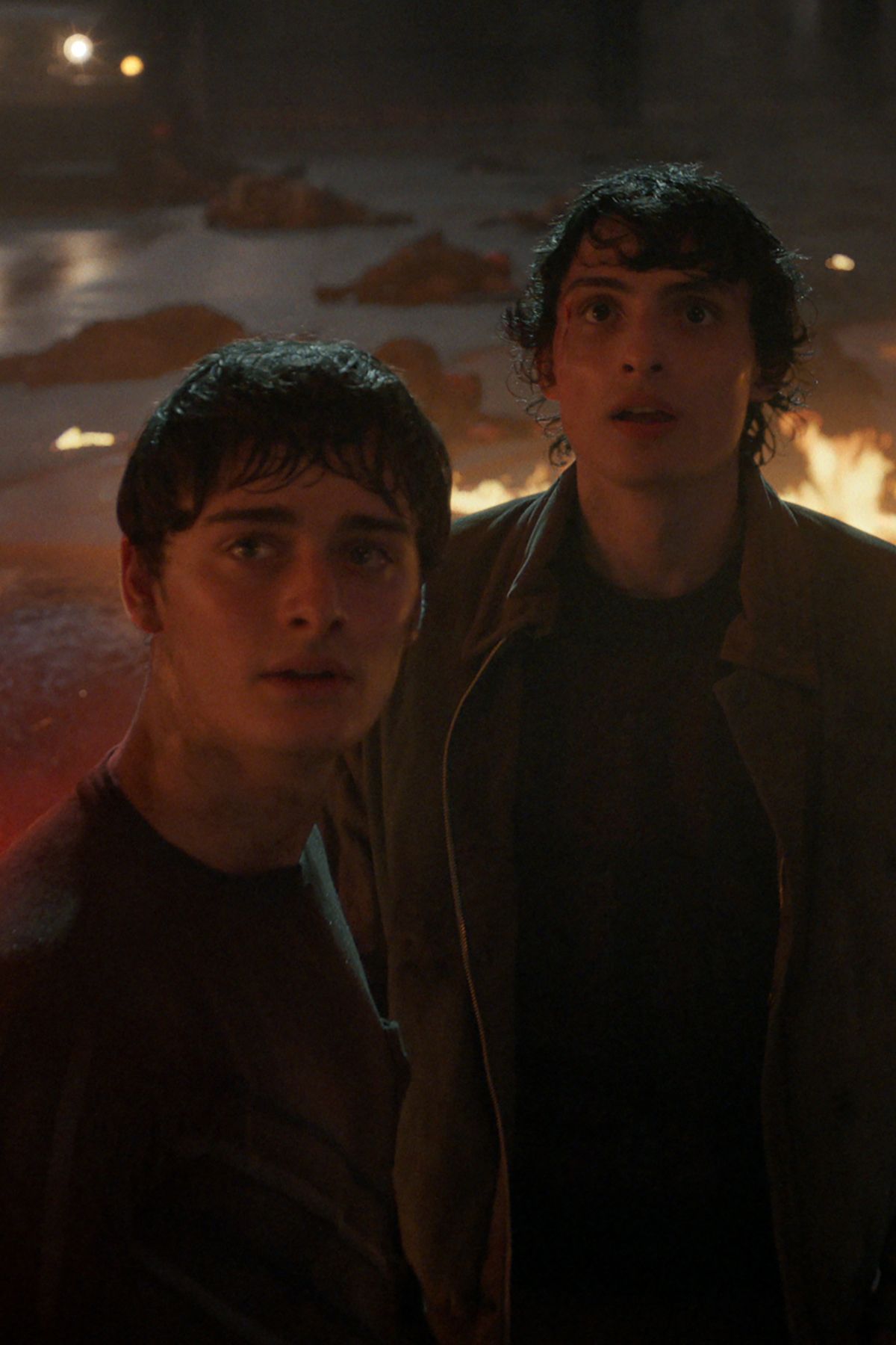 Image may contain Noah Schnapp Finn Wolfhard Fire Flame Face Head Person Photography Portrait Adult and Clothing